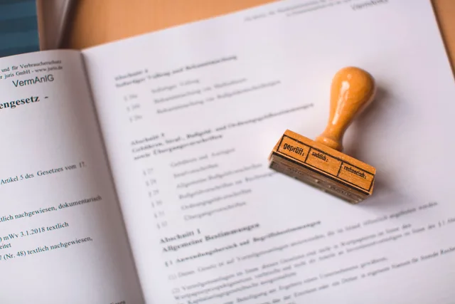 Close-up of a legal document with a wooden stamp placed on top, highlighting verification. Dokumentation for underleverandørers regelefterlevelse